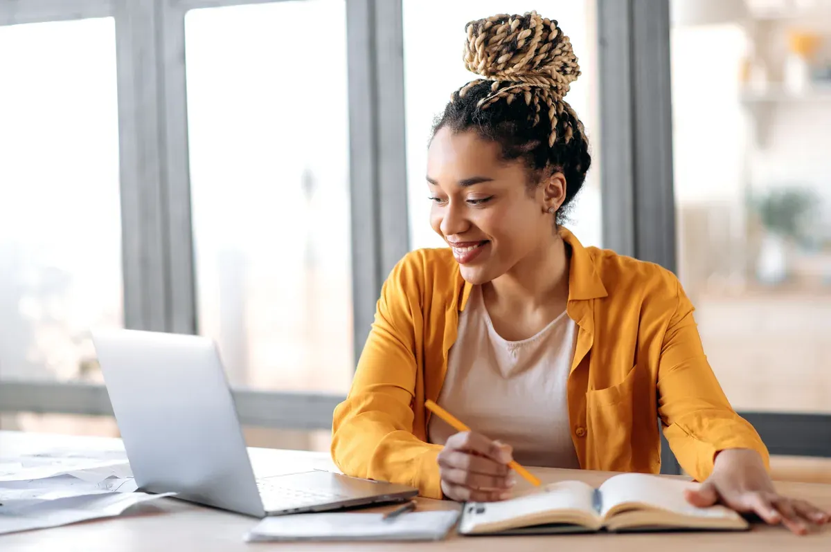 Adult learner studying the Accounting Specialist Online course on a laptop while writing notes