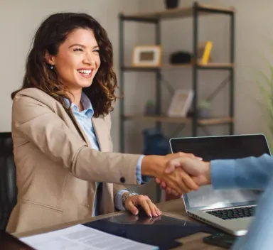 Ascendra graduate shaking hands with an employer across a desk after a successful job interview